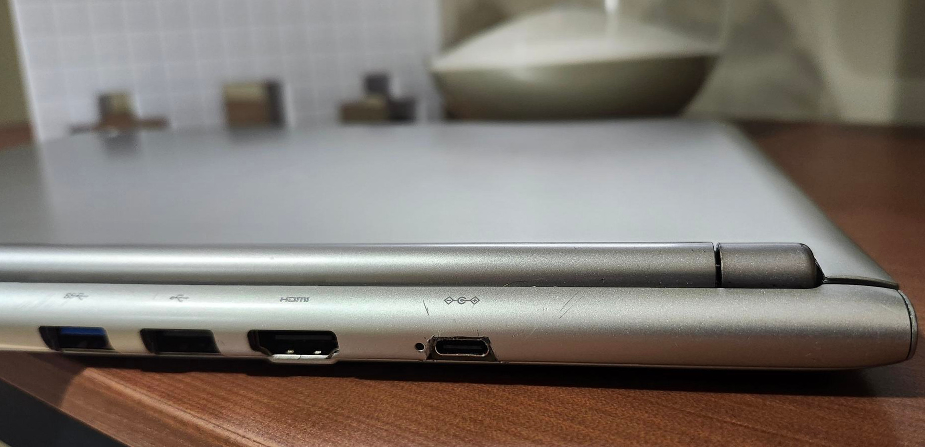 USB-C port on back of Chromebook is flush but the hole it fits in is slightly too large and roughly cut. A small LED indicator to the left of the port is intact.